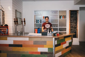Friendly staff member standing near the reception or bar table, welcoming guests at Dildo Brewing Co. Bottle Shop on Water Street, St. John's.